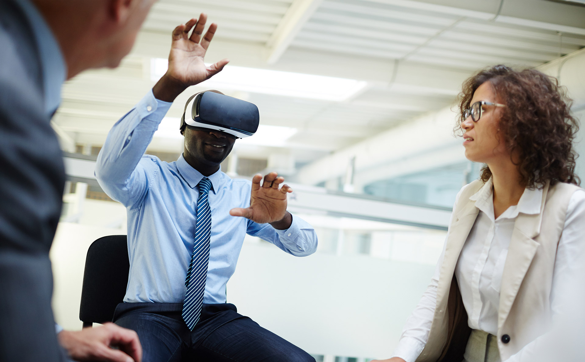 Colleagues looking at businessman with vr headset taking part in virtual conference or webinar.